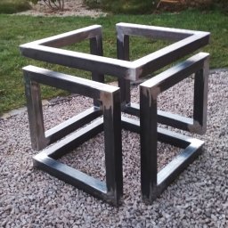 HYDROMIRO-SPAW Mirosław Rękawik - Metalowa konstrukcja przestrzenna w kształcie sześcianu, wykonana z profili, ustawiona na żwirowym podłożu z trawnikiem w tle.