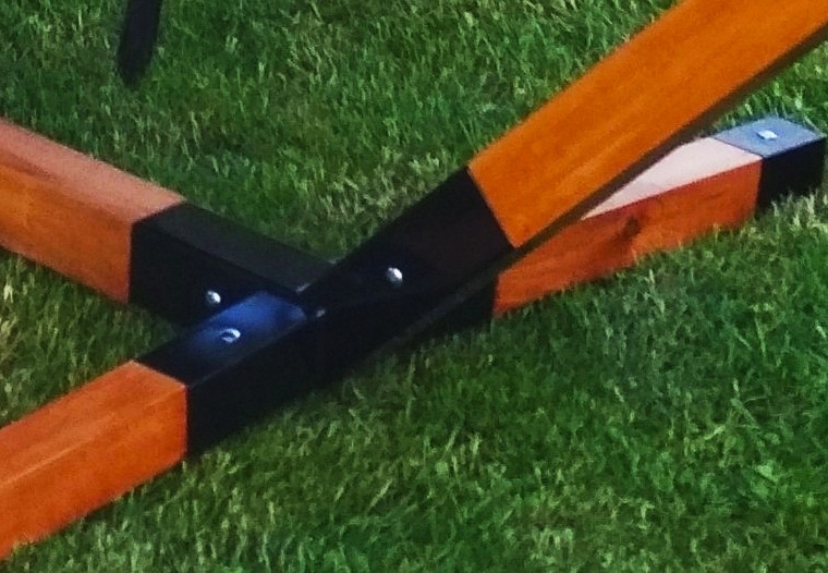 Połączenie drewnianych belek z metalowymi elementami mocującymi na trawie.