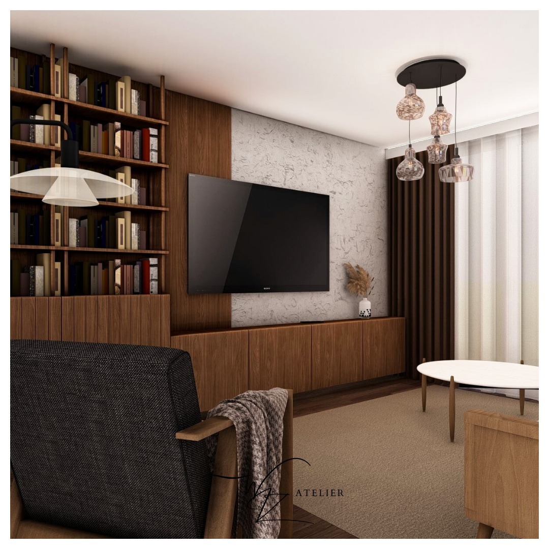 Nowoczesny salon z drewnianą zabudową biblioteczną, telewizorem na ścianie o fakturze betonu, szklanymi lampami wiszącymi i ciemnoszarym fotelem z pledem w pierwszym planie.