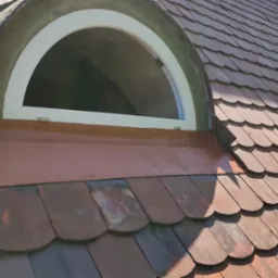 Dach z brązowej dachówki ceramicznej z oknem w kształcie półkola, biała rama okienna, widoczne obróbki blacharskie. Dachówka karpiówka.