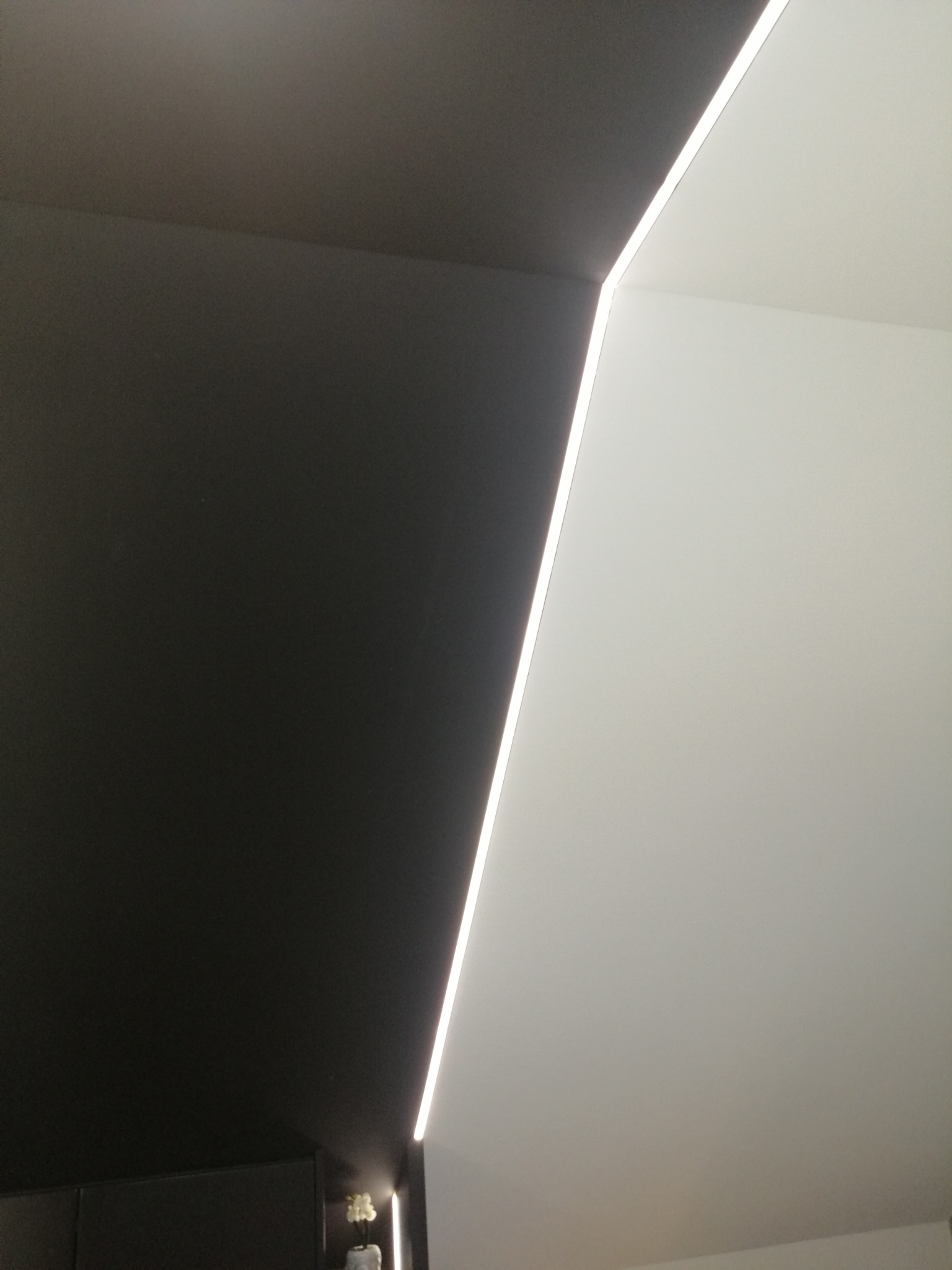 Czarne i białe ściany z oświetleniem LED wzdłuż krawędzi, tworzące nowoczesny, minimalistyczny design wnętrza.