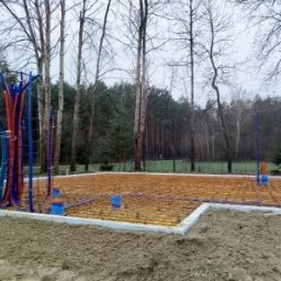Nortegard Sp. z o.o. - Przygotowanie fundamentów pod budowę domu: izolacja, instalacje wodno-kanalizacyjne, zbrojenie. Widok na las w tle, pochmurny dzień.