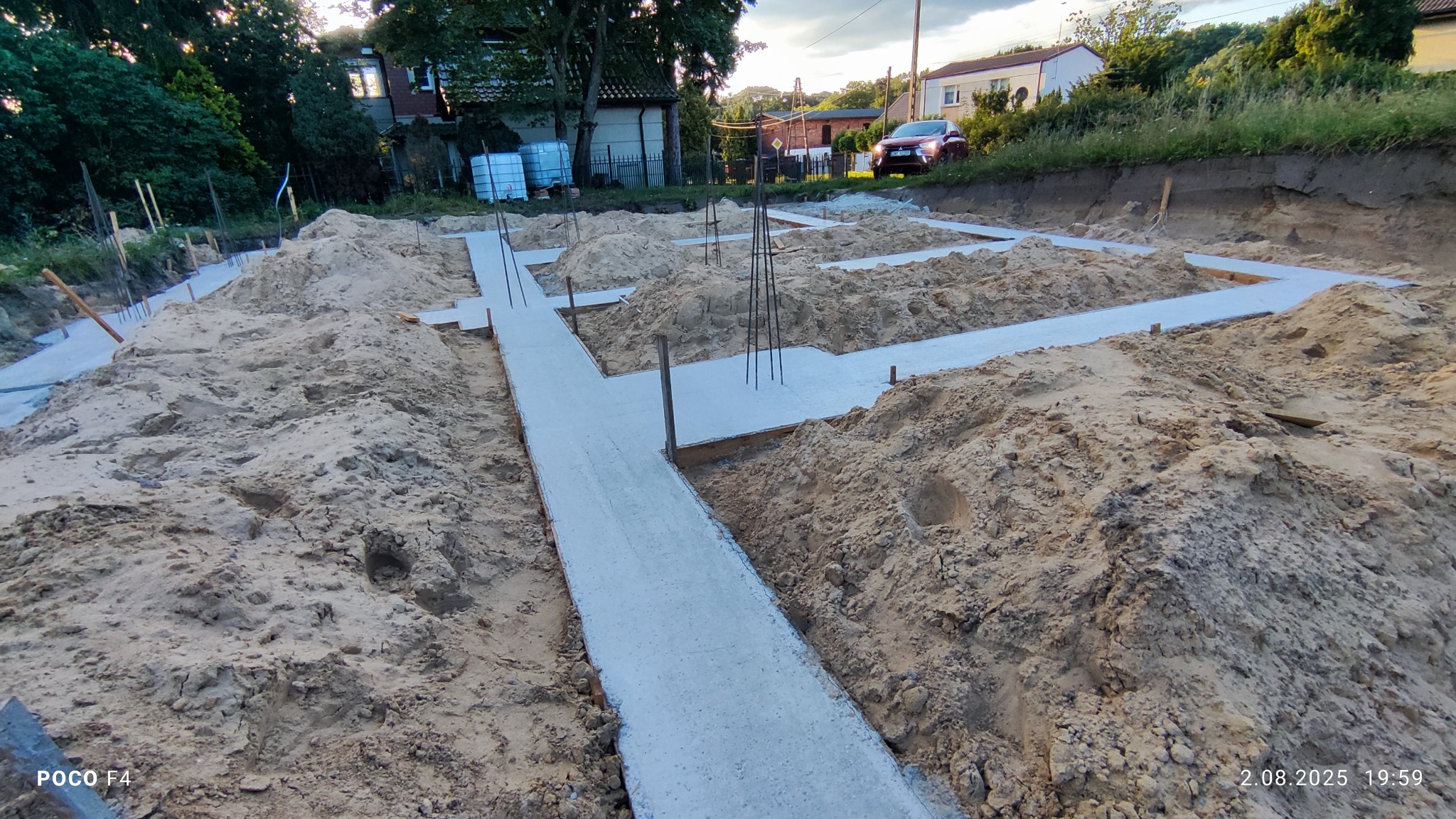 Ławy fundamentowe domu jednorodzinnego w Szczecinie. Widoczne zbrojenia i betonowe wylewki. Prace ziemne i przygotowanie do dalszych etapów budowy.