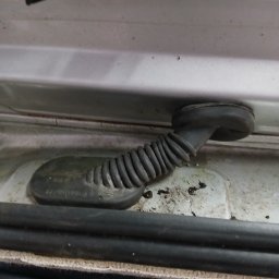 Car Serwis Sławno - Gumowa osłona przewodów elektrycznych w karoserii samochodu marki Ford, widoczne zabrudzenia.