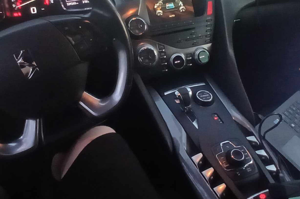 Wnętrze samochodu marki Peugeot z widoczną deską rozdzielczą, kierownicą i panelem sterowania, z laptopem podłączonym do systemu diagnostycznego.