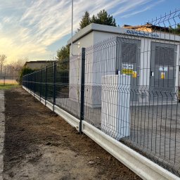 TYMACOMPANY SPÓŁKA Z OGRANICZONĄ ODPOWIEDZIALNOŚCIĄ - Nowoczesne ogrodzenie panelowe w kolorze grafitowym z podmurówką betonową, chroniące transformator Elektromontaż-Lublin, tło: błękitne niebo z pierzastymi chmurami.