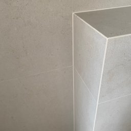 SERHII - BUD SERHII PINKO - Beżowe płytki ceramiczne ułożone na ścianie i wnęce, z widocznymi fugami. Minimalistyczny design, neutralna kolorystyka i precyzyjne wykończenie.