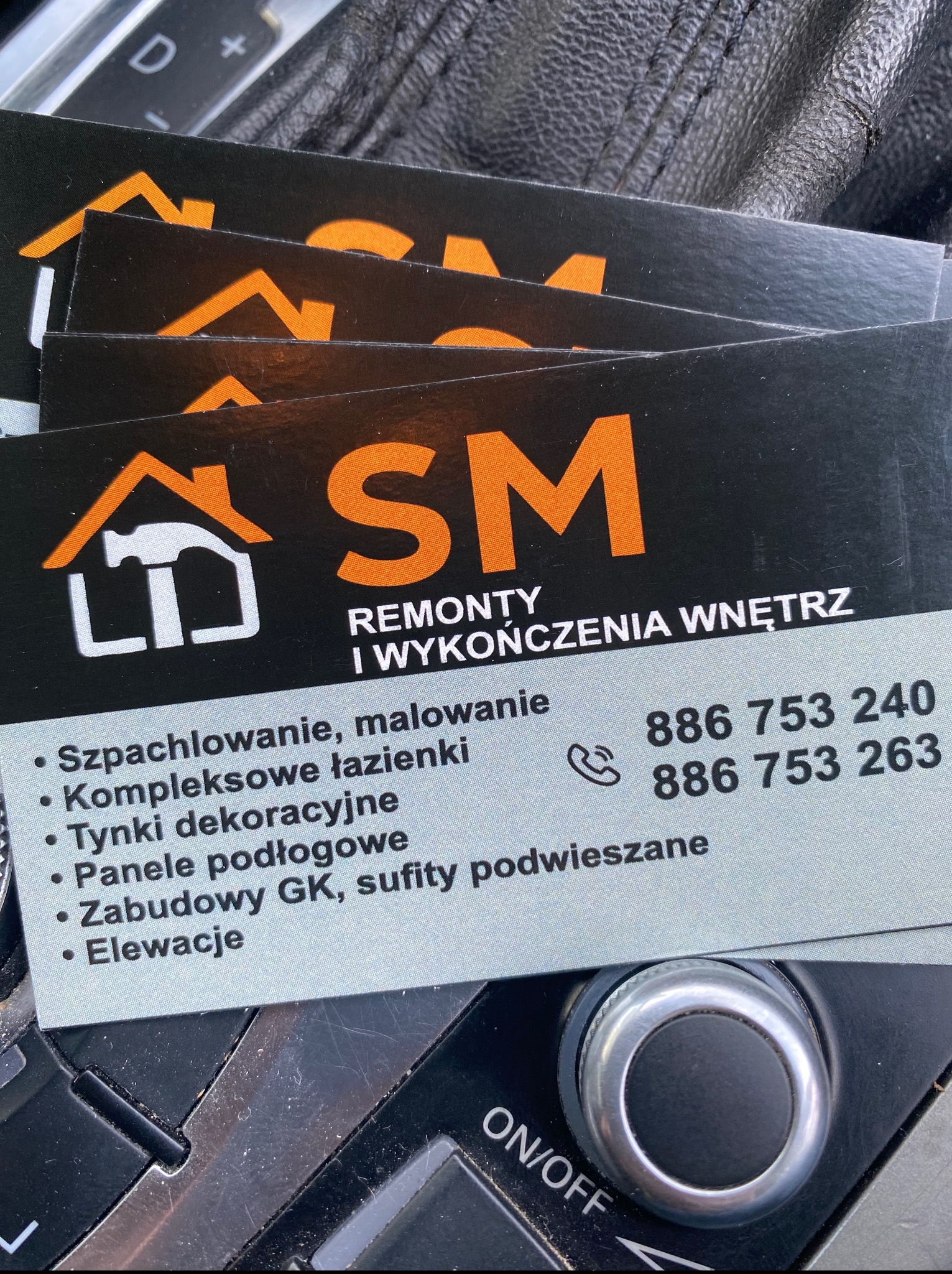 Wizytówki firmy SM Remonty i Wykończenia Wnętrz z ofertą szpachlowania, malowania, kompleksowych łazienek, tynków dekoracyjnych, paneli podłogowych, zabudów GK i elewacji.