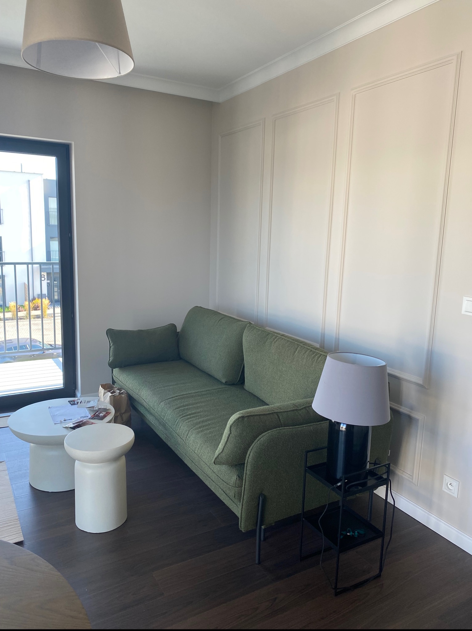 Eleganckie wykończenie ścian w salonie z zieloną sofą i stolikiem. Dekoracyjne panele ścienne tworzą subtelny wzór. Nowoczesne wnętrze z dbałością o detale.