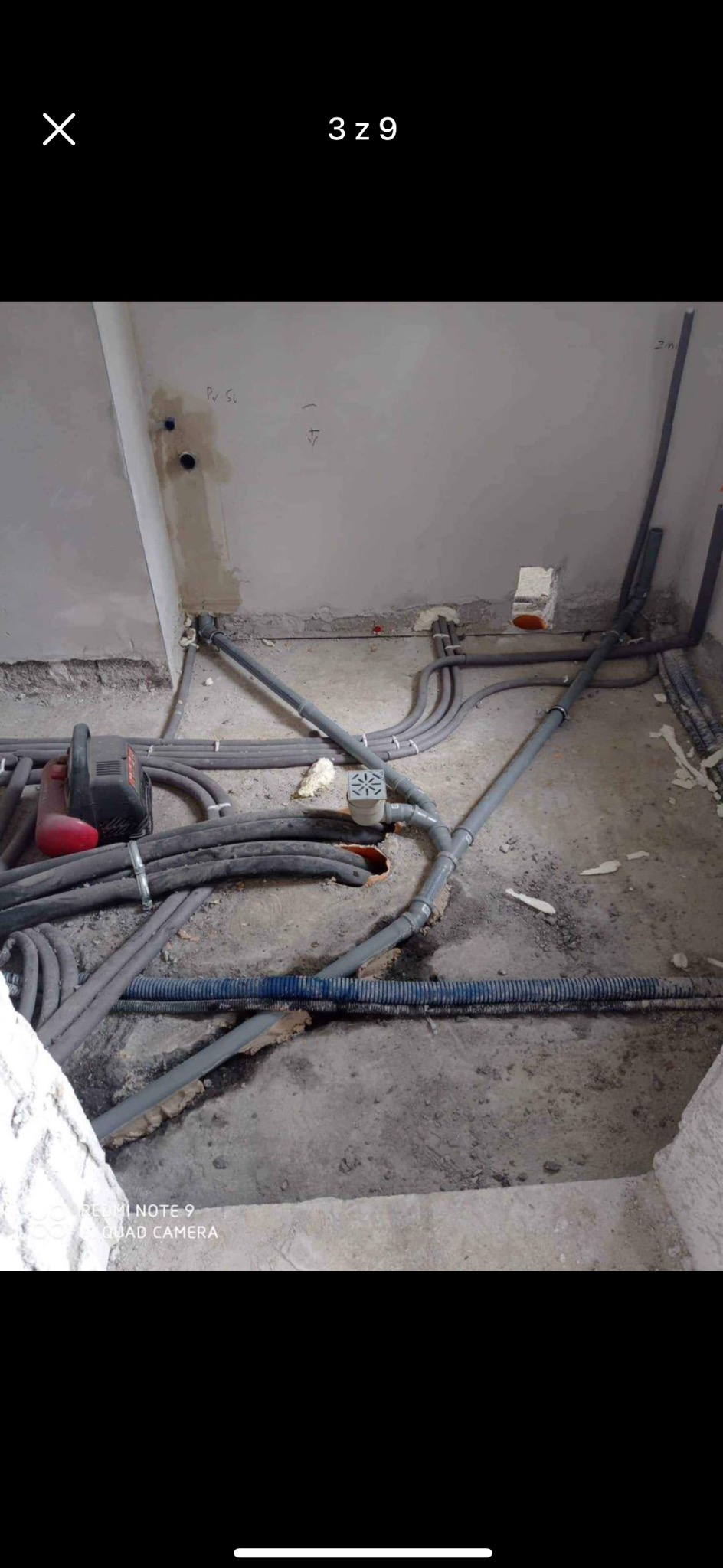 Hydrauliczne i grzewcze rury rozprowadzone w surowym stanie podłogi podczas instalacji, widoczny odpływ podłogowy i bruzdownica.