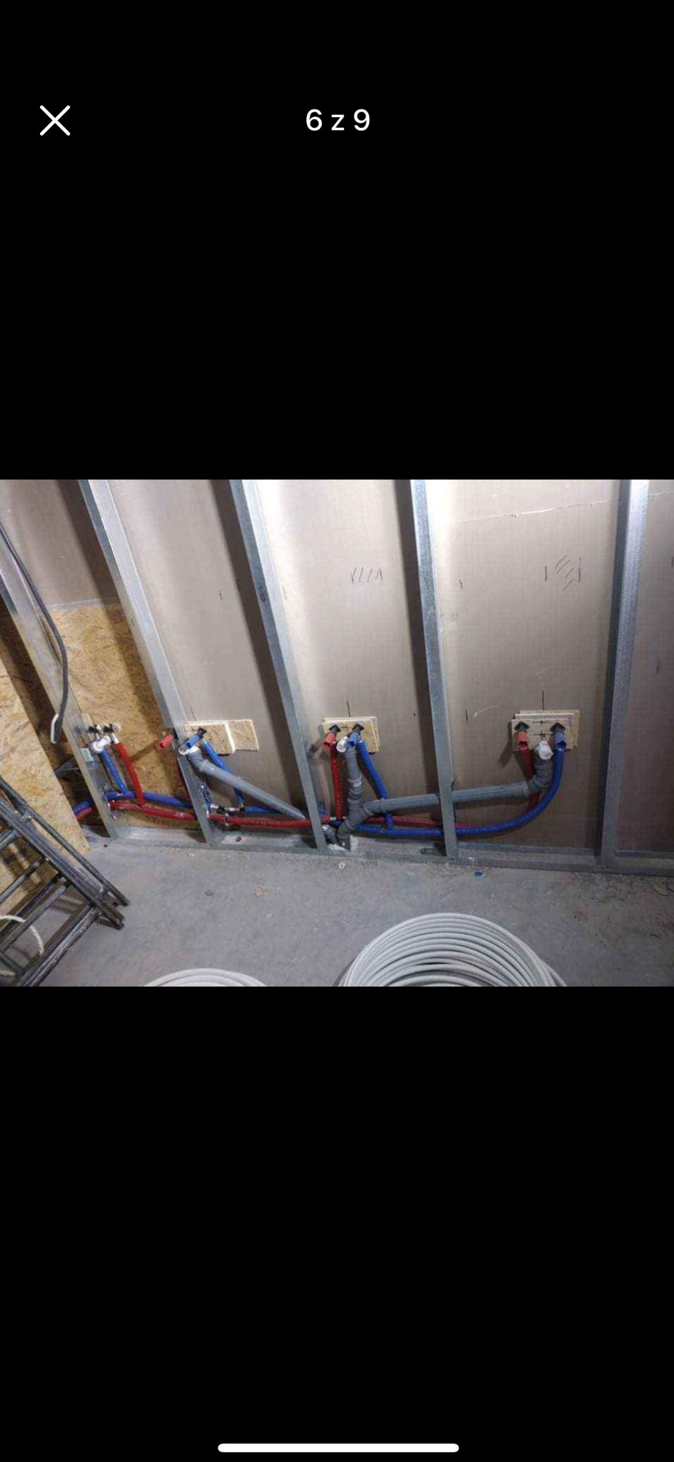 Wewnętrzne instalacje wodne i grzewcze w trakcie montażu w budynku, widoczne rury z tworzywa w kolorach niebieskim i czerwonym, częściowo ukryte w ścianie z płyt gipsowo-kartonowych na metalowym...