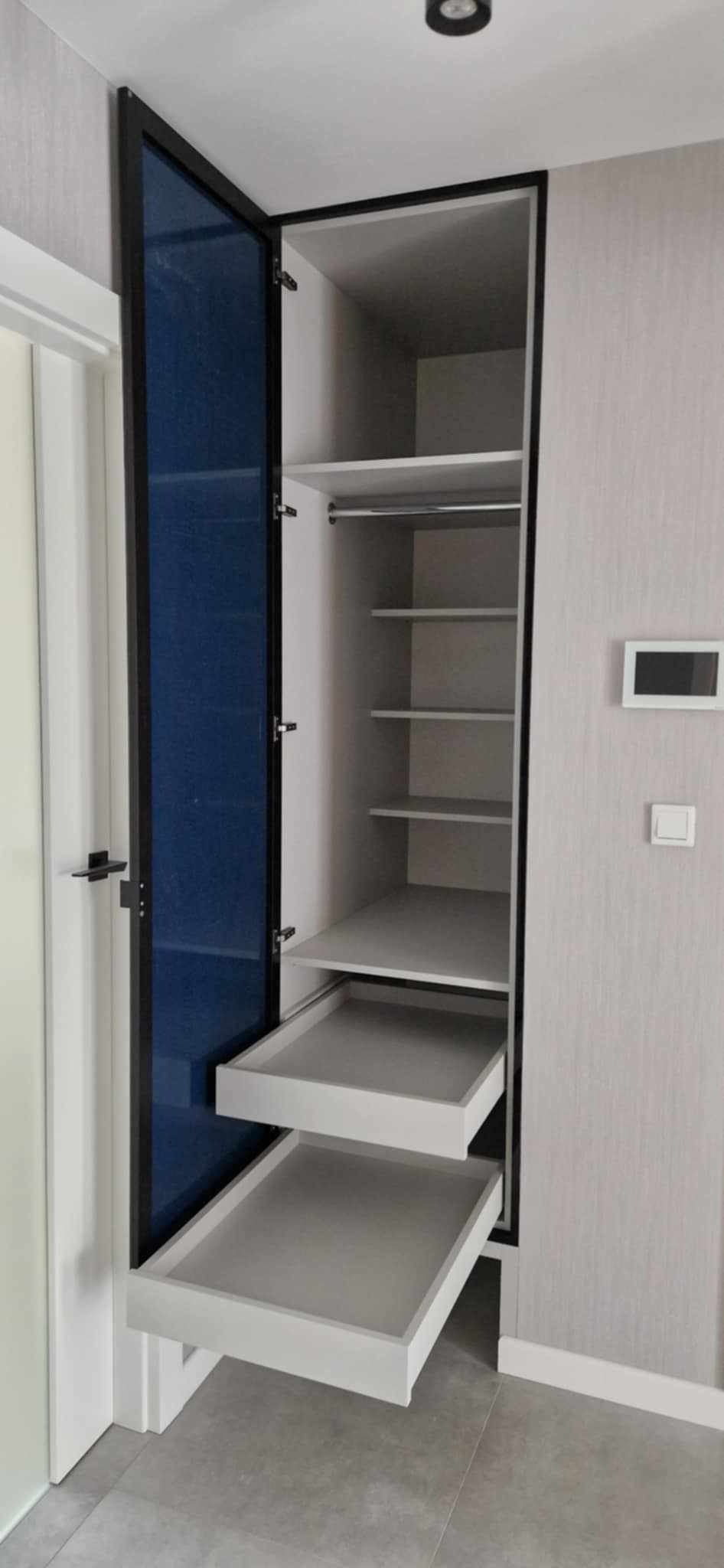 Szafa wnękowa z szufladami i niebieskimi drzwiami w Tarnowie. Nowoczesny design, jasne wnętrze, minimalistyczny styl. Funkcjonalne rozwiązanie do przechowywania.