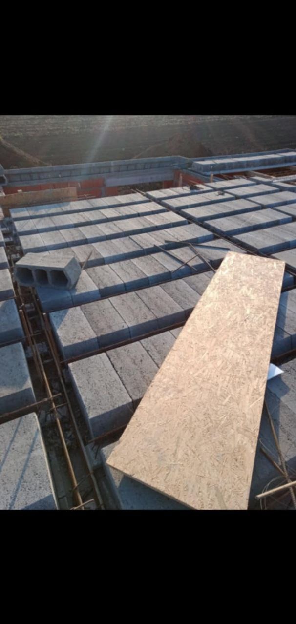 Wieniec stropowy z betonowych pustaków szalunkowych, zbrojony stalą, z deską szalunkową na wierzchu, w trakcie budowy domu, widok z góry.