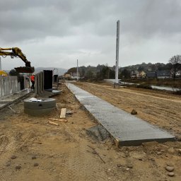 Royal Bud - Wykop z betonową wylewką w szalunku, zbrojone prefabrykaty i koparka w tle, teren budowy w pochmurny dzień.