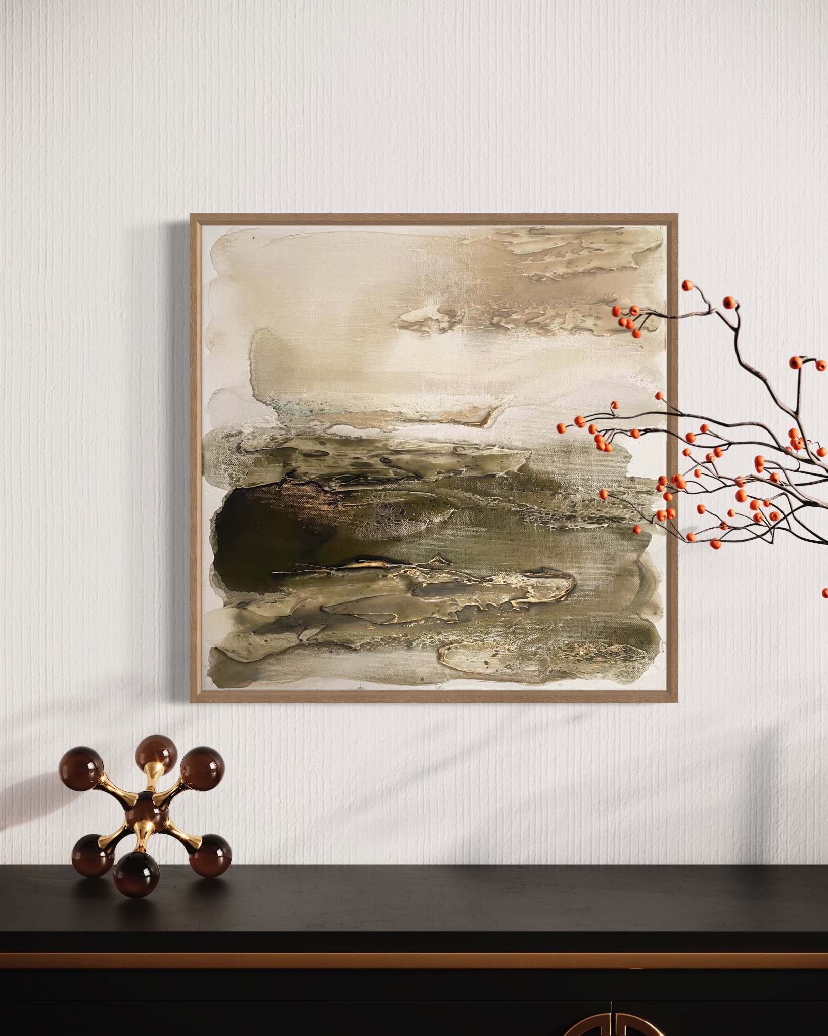 Abstrakcyjny obraz w drewnianej ramie, utrzymany w odcieniach beżu i brązu, zawieszony nad czarną komodą z dekoracyjnym elementem w kształcie molekuły i gałązką z pomarańczowymi owocami.