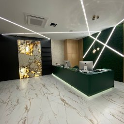 Vitalii Herasymenko - Nowoczesne wnętrze recepcji z podświetlaną ladą w kolorze butelkowej zieleni, marmurową posadzką, dekoracyjną ścianą z mchu i podświetleniem LED na suficie.