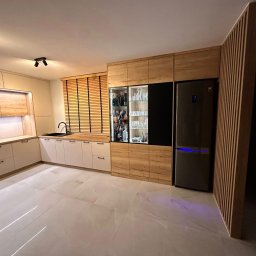 Ewel-Meb Ewelina Jasionowska Meble na wymiar - Nowoczesna kuchnia na wymiar z drewnianymi akcentami, zabudową lodówki i barkiem z oświetleniem, uchwyty listwowe, marmurowe płytki podłogowe.