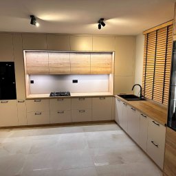 Ewel-Meb Ewelina Jasionowska Meble na wymiar - Jasna kuchnia na wymiar z drewnianym blatem i żaluzjami, oświetlenie punktowe. Fronty szafek w odcieniach beżu i kremu, nowoczesny design.