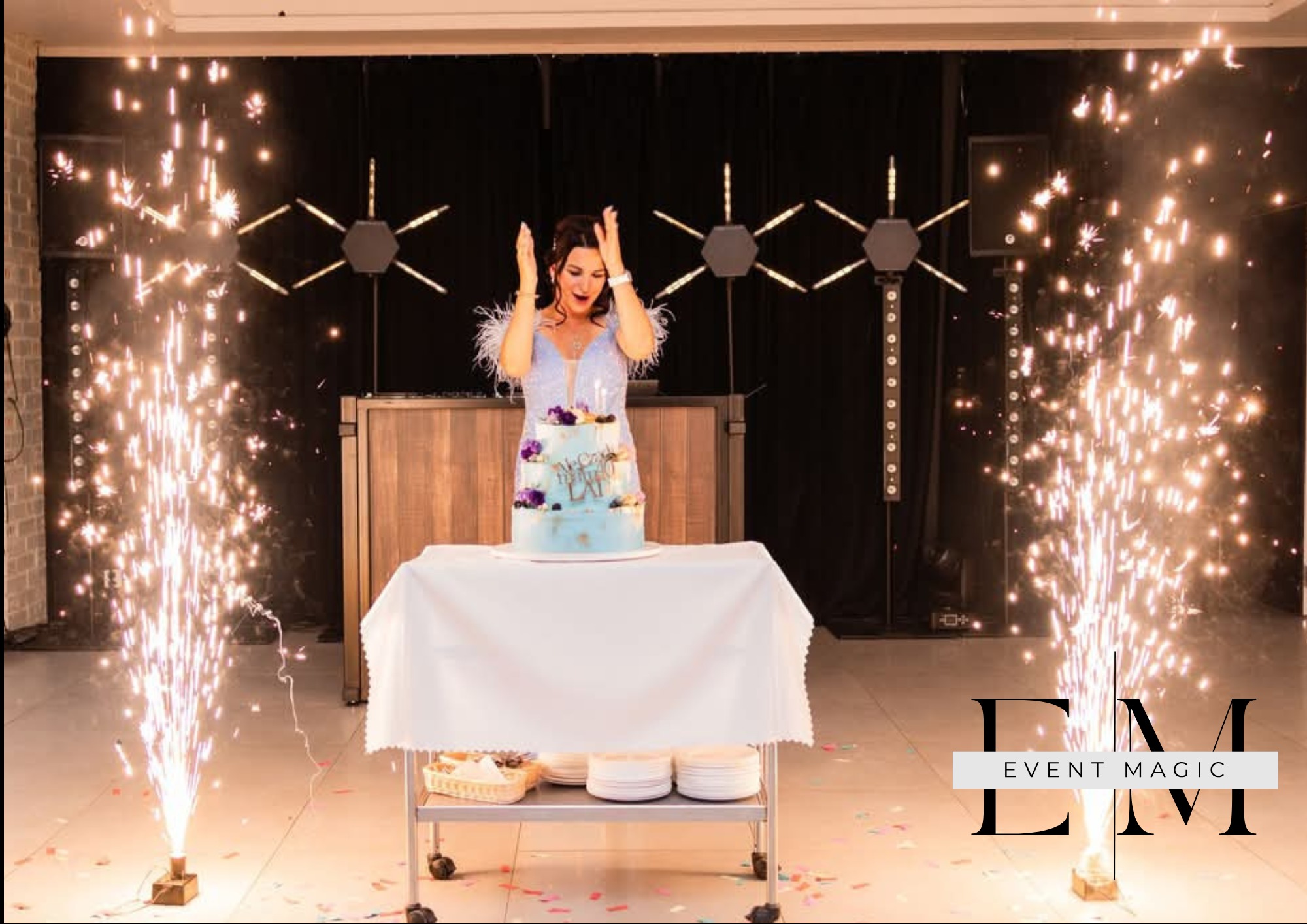 Uśmiechnięta kobieta w sukience z piórami, tort urodzinowy, zimne ognie. Dekoracje imprezowe, oświetlenie sceniczne, mobilny bar.