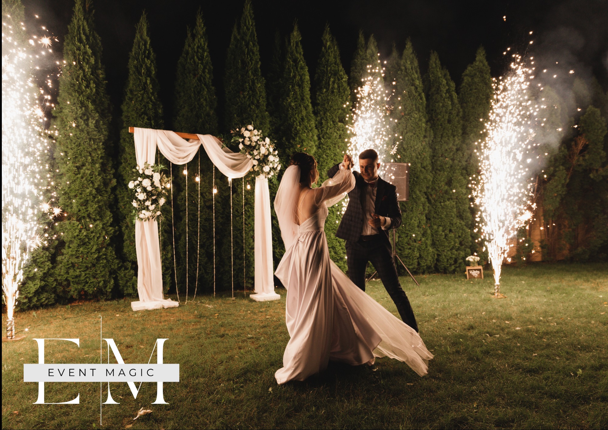 Para młoda tańczy na tle fontann iskier i dekoracji ślubnych w ogrodzie, nocna sceneria, romantyczna atmosfera.