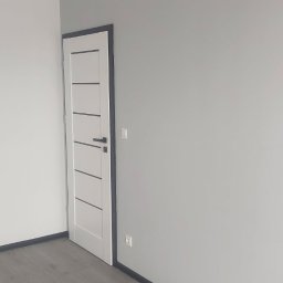 OdNowa FIRMA OGÓLNOBUDOWLANA BEATA KOWALCZYK - Pokój po remoncie: szare ściany, panele podłogowe w odcieniach szarości, białe drzwi z szarymi akcentami i szare listwy przypodłogowe.