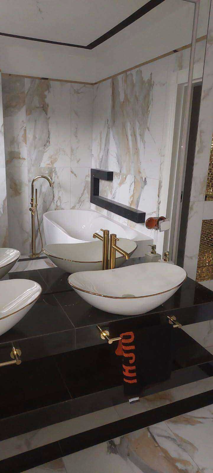 Wykończona łazienka w Żorach z umywalkami nablatowymi w stylu glamour, złote baterie i marmurowe płytki na ścianach.