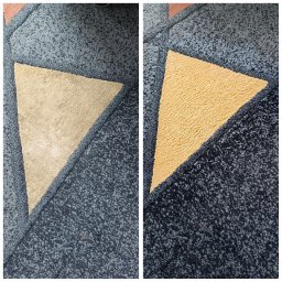 ... - Fragment dywanu z wyraźnym podziałem na obszar wyczyszczony (żółty trójkąt) i obszar przed czyszczeniem (beżowy trójkąt) na tle wzorzystej, niebiesko-szarej powierzchni.