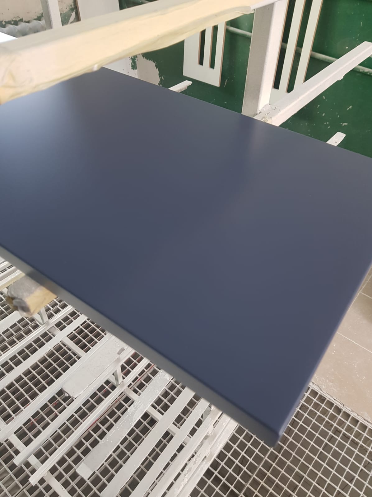 Granatowy, lakierowany front meblowy na kratownicy lakierniczej, widoczny z góry. Element w trakcie procesu produkcji mebli na wymiar.