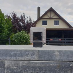 ML AUTOMATYK MAREK LIS - Fotokomórka FAAC zamontowana na szarym, kamiennym słupku bramy wjazdowej, na tle domu z garażem i zielenią.