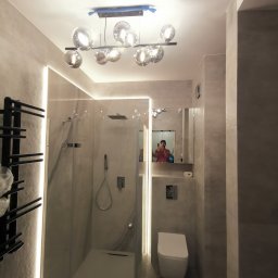 Lutsyk - Nowoczesna łazienka w odcieniach szarości z kabiną prysznicową typu walk-in, podświetleniem LED wzdłuż ścian i designerską lampą sufitową z szklanymi kulami.