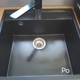 Natalia Rydzyńska - Czarny, kwadratowy zlew granitowy z chromowaną baterią, widoczny po czyszczeniu, z napisem 'Po' w prawym dolnym rogu.
