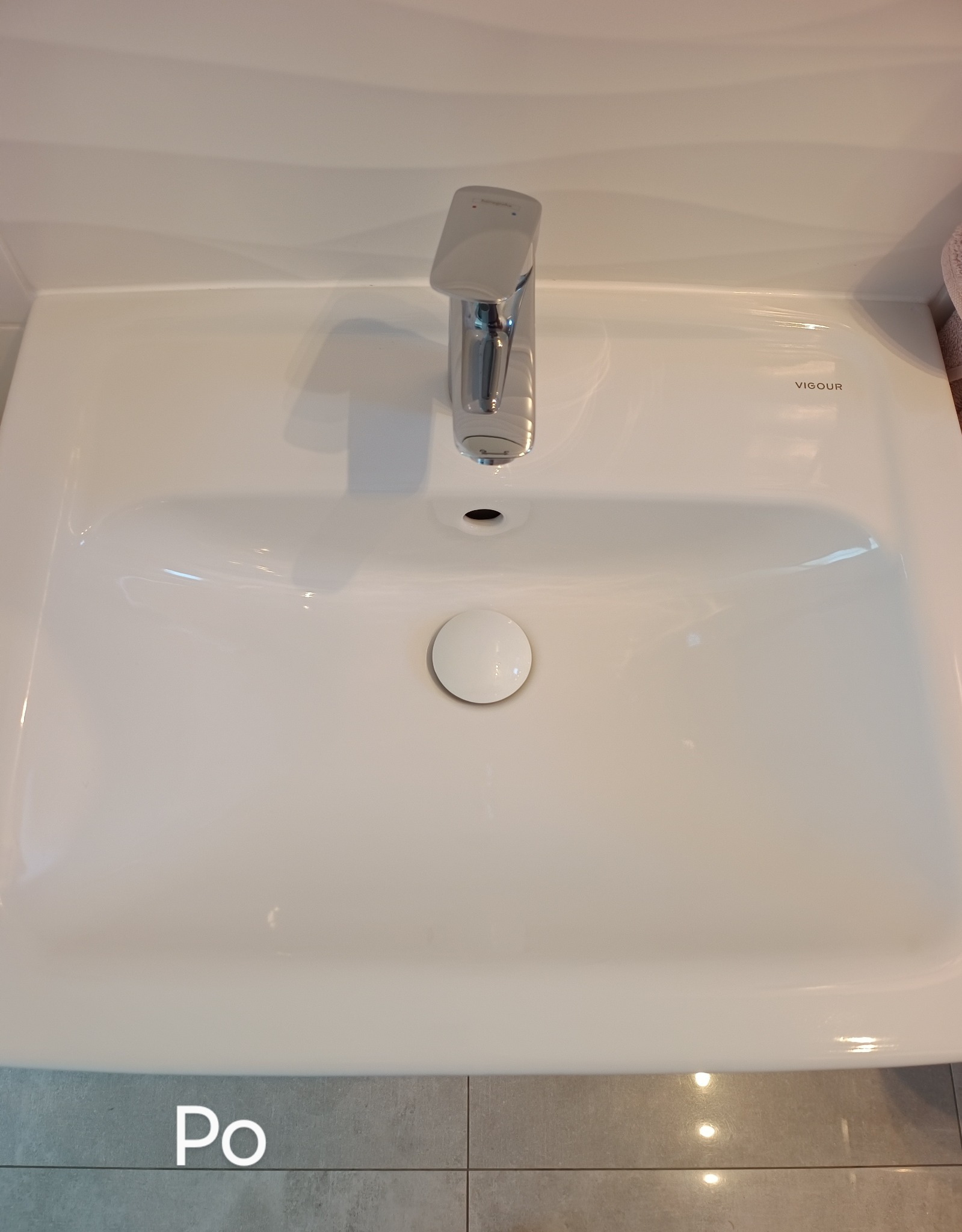 Biała, czysta umywalka VIGOUR z chromowaną baterią i zamkniętym odpływem, widok z góry, po zakończonym sprzątaniu.