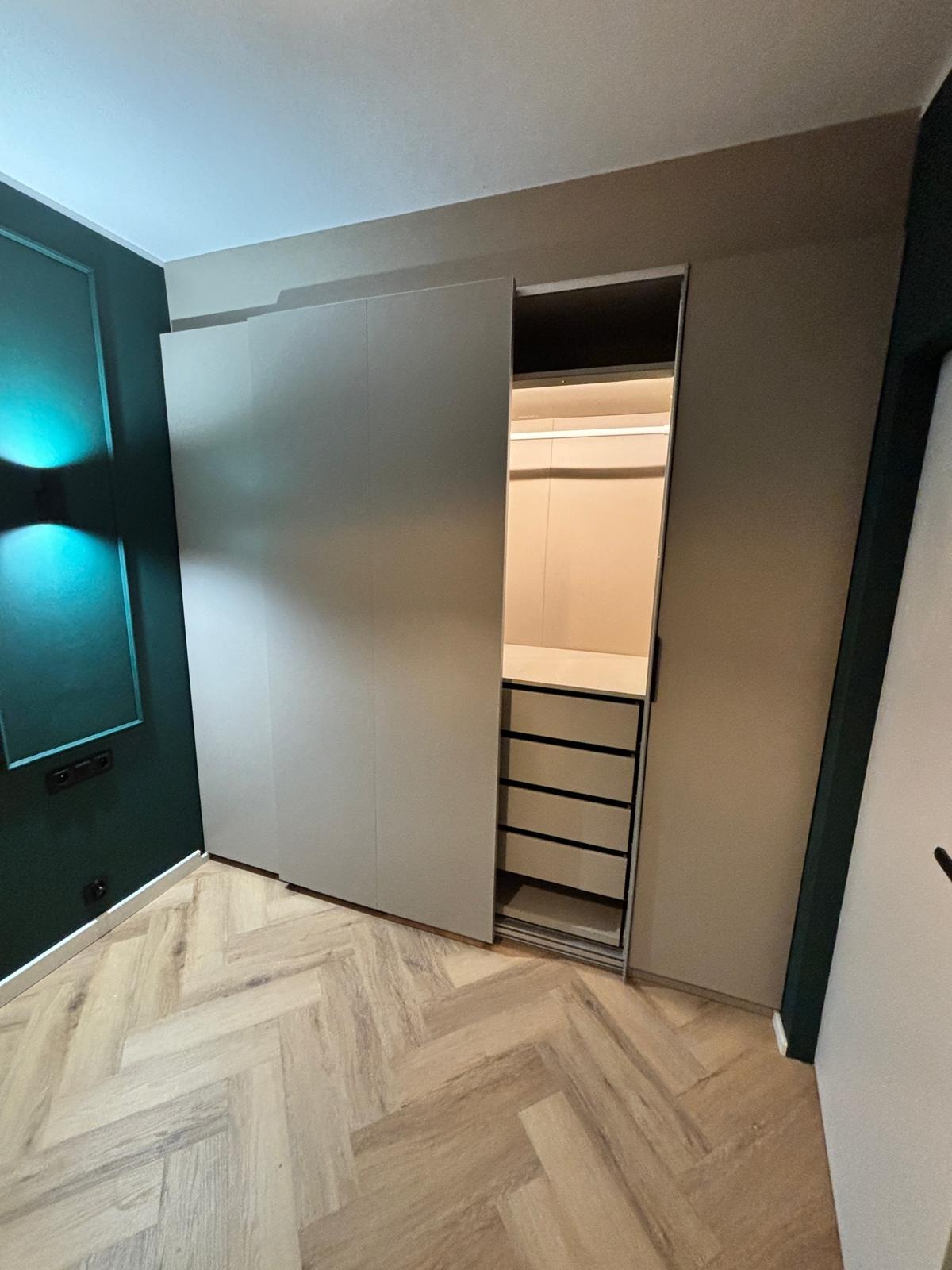 Nowoczesna szafa wnękowa z przesuwnymi drzwiami, widoczne szuflady i oświetlenie LED wewnątrz, wykończenie wnętrz w Bydgoszczy.