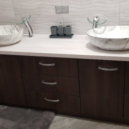 Rystol sp.z oo - Nowoczesna łazienka z dwoma umywalkami w marmurowym wzorze, osadzonymi na szafce z ciemnego drewna. Minimalistyczne baterie i akcesoria dopełniają aranżację.