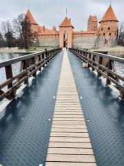 Długi most z płyt drogowych prowadzący do średniowiecznego zamku na wyspie, widok z perspektywy pieszego.