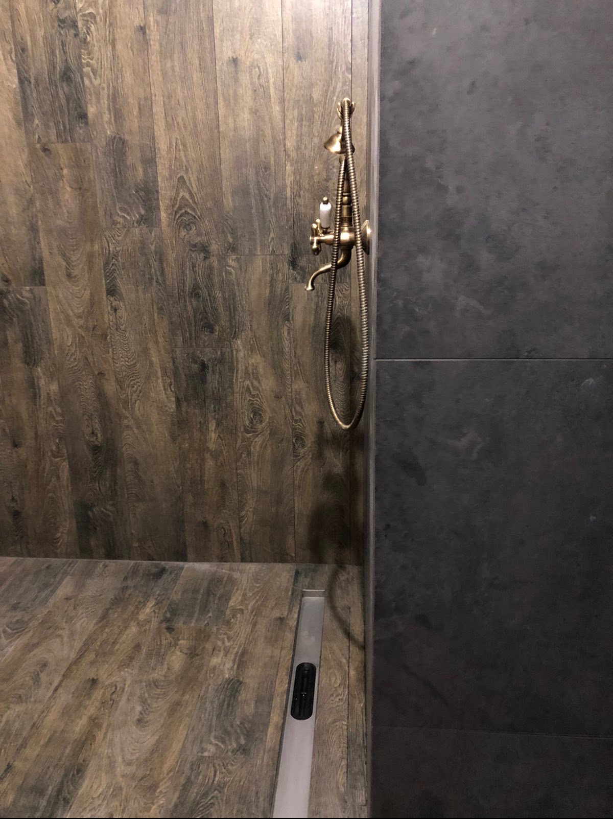 Nowoczesna kabina prysznicowa z drewnopodobnymi płytkami i deszczownicą w stylu retro. Widoczny odpływ liniowy.