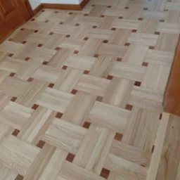 Parkiet w jodełkę francuską z jasnego drewna i ciemnymi akcentami, ułożony w Leoncin. Wykończenie podłogi z listwami przypodłogowymi.