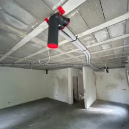 Szara instalacja wentylacyjna z czerwonymi elementami zamocowana do sufitu w surowym stanie w nowym pomieszczeniu.