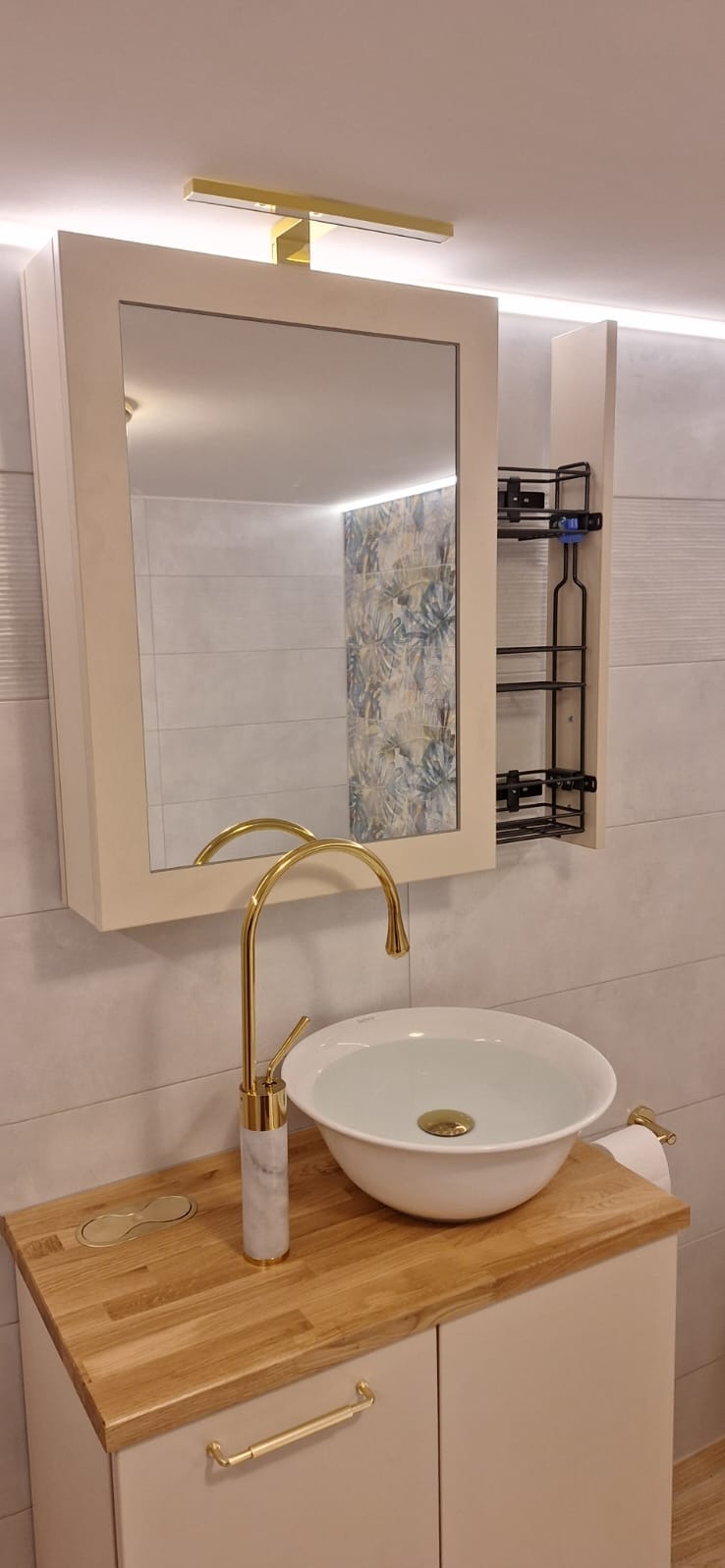 Nietypowa zabudowa łazienki z koszem cargo ukrytym za lustrem.