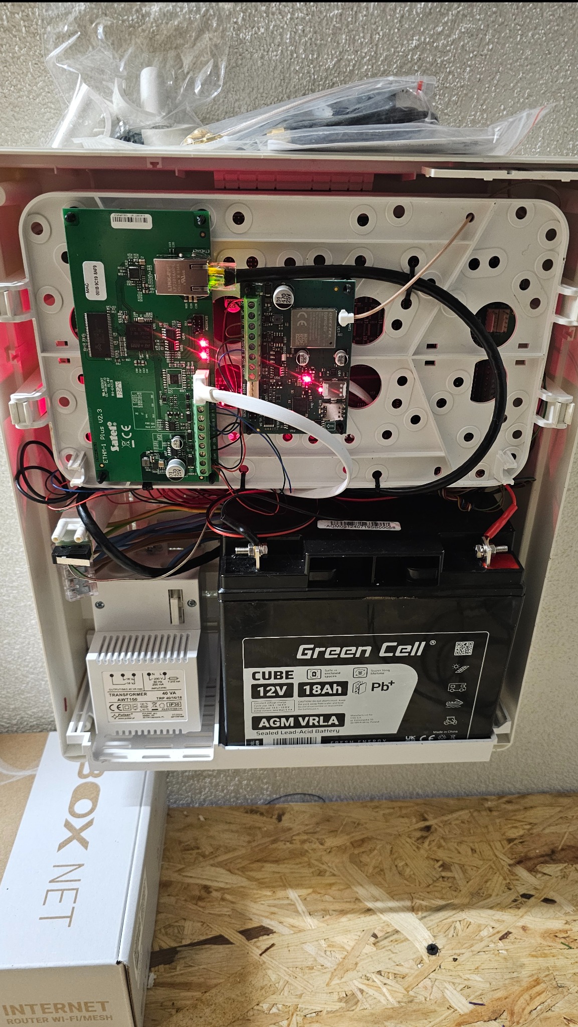 Wnętrze centrali alarmowej z akumulatorem Green Cell. Widoczne moduły Satel ETHM-1 Plus, transformator Pulsar AWT150 i okablowanie. Elementy systemu alarmowego w obudowie.