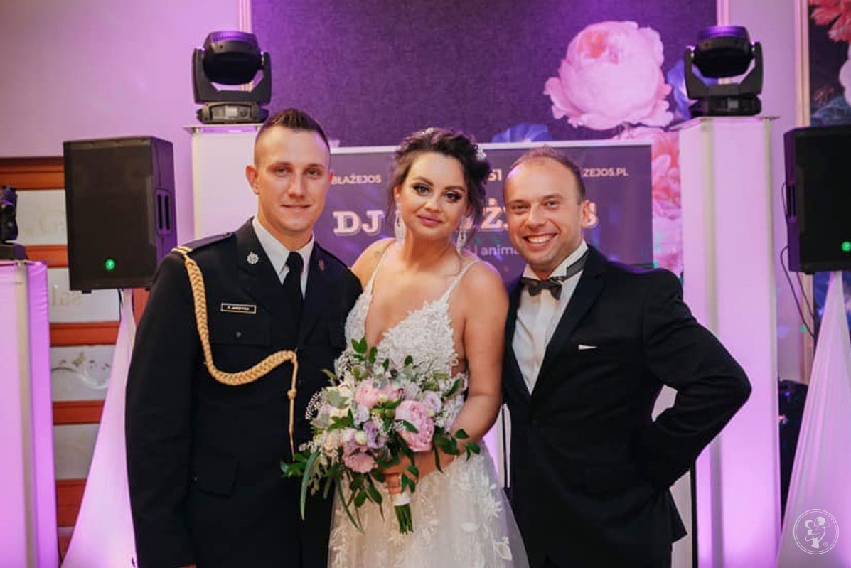 Panna młoda z bukietem kwiatów pozuje z dwoma mężczyznami: jeden w galowym mundurze strażackim, drugi w smokingu z muszką, na tle sceny z oświetleniem DJ-skim.