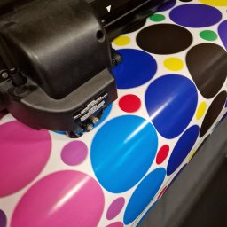 Realizacja wydruku wielkoformatowego na Dzień kropki - kolorowe naklejki wycinane na ploterze, przygotowane na wydarzenie edukacyjne.