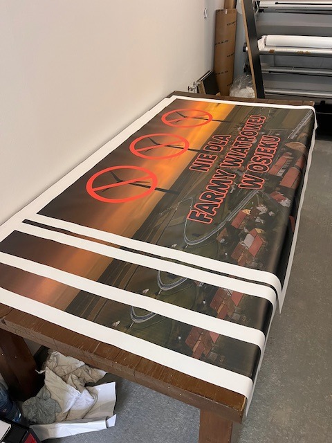 Wydrukowane czekające na obróbkę i oczkowanie banery protestacyjne.