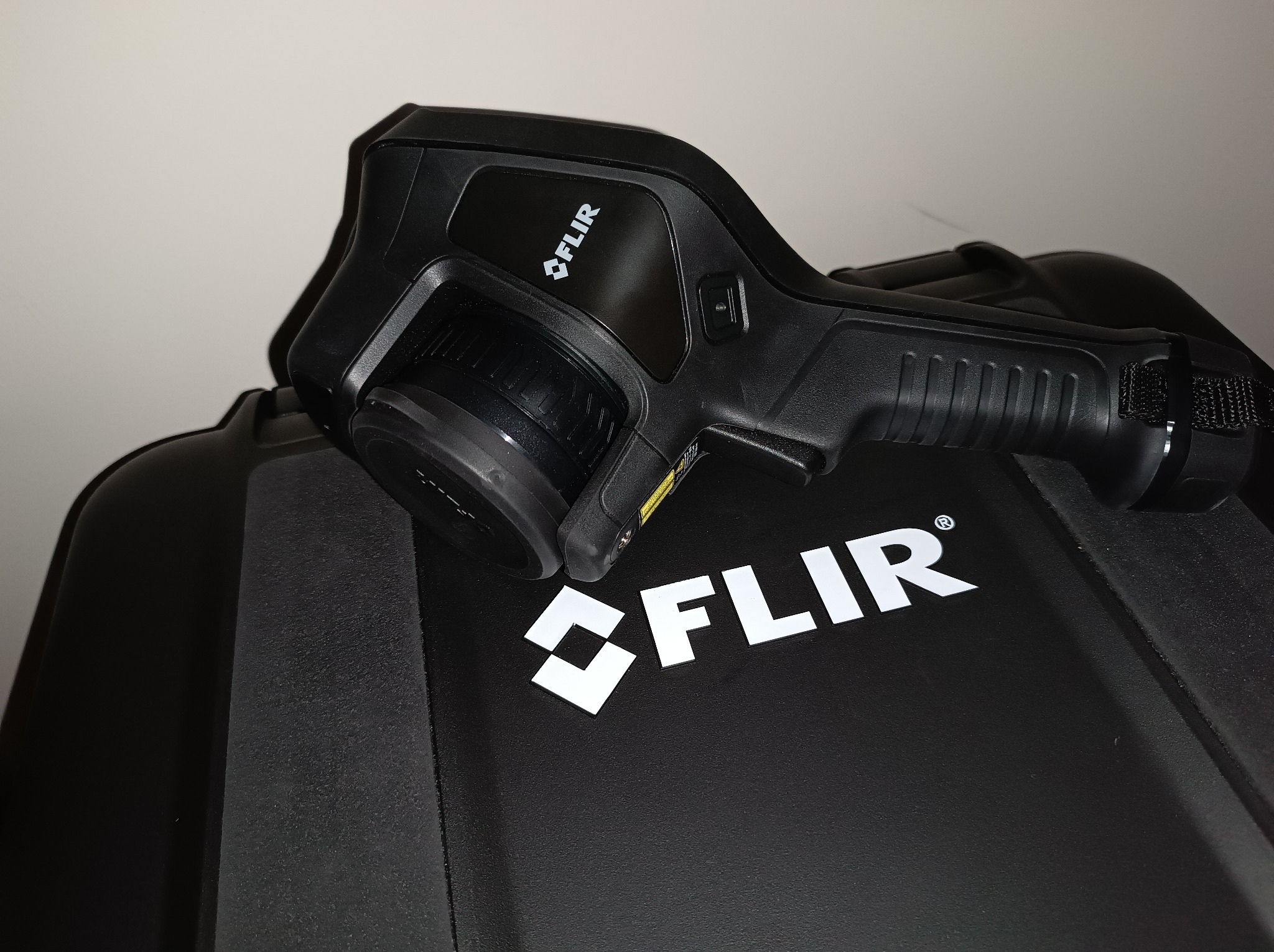 Czarny termowizor FLIR leżący na czarnej walizce z białym logo FLIR.