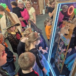 Kids Arena - Grupa dzieci w kostiumach halloweenowych pozuje do zdjęcia w fotolustrze z oświetleniem LED i dekoracyjną ramą.