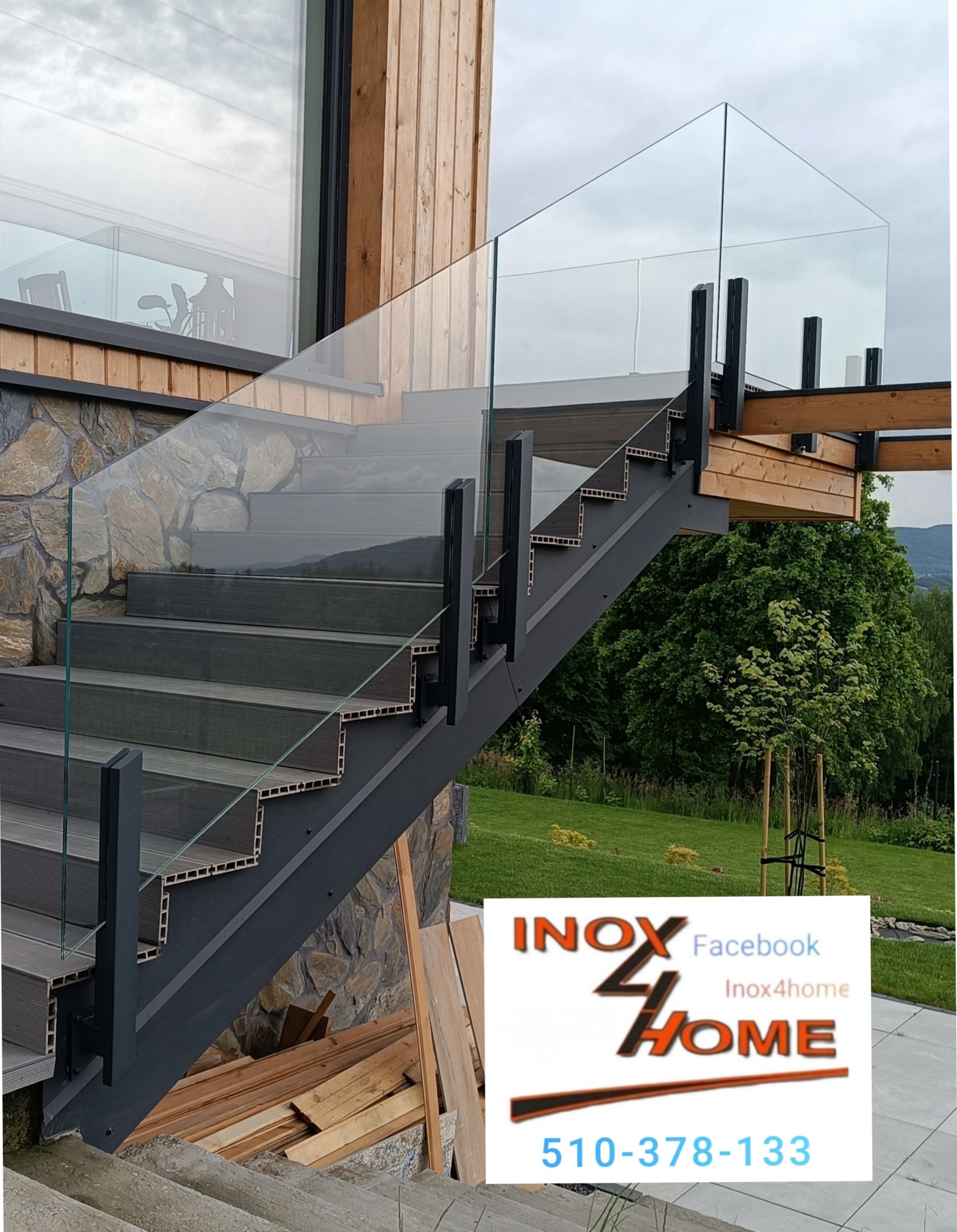 Szklana balustrada na schodach zewnętrznych z metalową konstrukcją, widok z dołu, na tle kamiennej ściany i zieleni. Nowoczesny design.