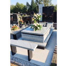 FLINTSTONE GRANIT I MARMUR SPÓŁKA Z OGRANICZONĄ ODPOWIEDZIALNOŚCIĄ - Jasnoszary granitowy pomnik z czarną tablicą nagrobną i bukietem kwiatów w wazonie, na cmentarzu.