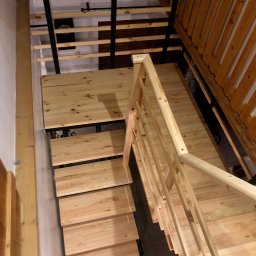 ELMAT Mateusz Ziętek - Drewniane schody z metalową konstrukcją nośną, widok z góry na stopnie i poręcze z jasnego drewna w surowym wykończeniu.