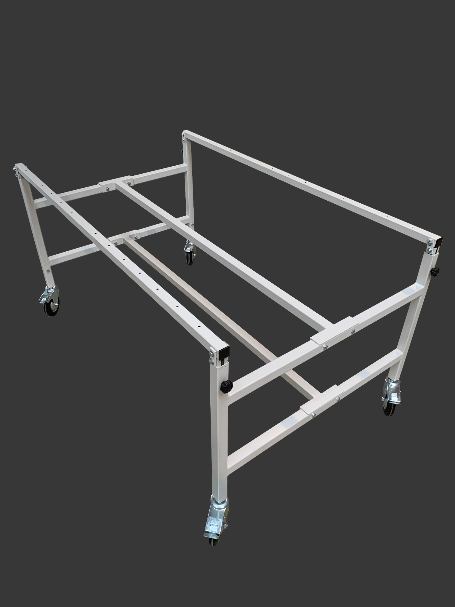 Metalowa rama konstrukcyjna na kółkach, spawana z profili, pomalowana na biało, widok z dołu pod kątem na szarym tle.