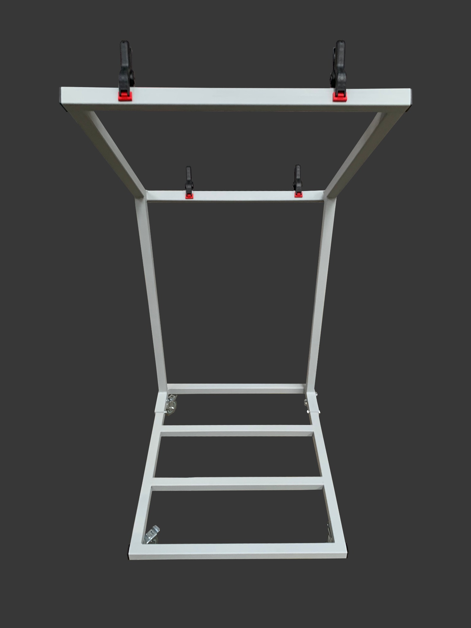 Biała, metalowa konstrukcja spawana z profili zamkniętych, z uchwytami zaciskowymi, widok z dołu na szarym tle.